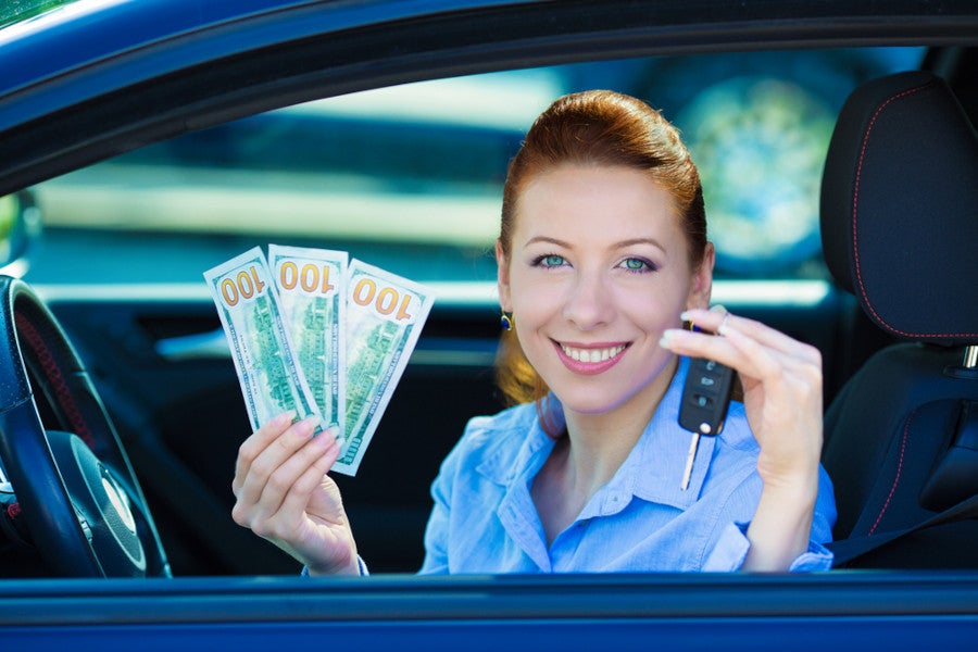 Woman hoding Cash in one hand and Car Key in another Hand Seating in Car.